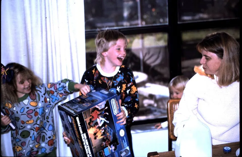 This is a photograph of photographer Adam Scott, as a child, opening his very first Nintendo Game System on Christmas Morning. The image, probably taken by his father, Jack Heilpern, shows his sister, Jessica Heilpern, and his mother, Merrie Heilpern.