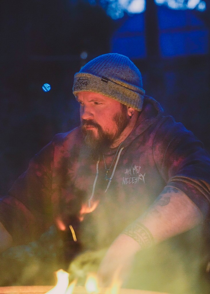 a self portrait of photographer Adam Scott on the night of Winter Solstice, sitting next to a fire.